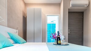 A hotel room with a bed, a minibar, a bathroom door, and an air conditioning unit. - La Smeralda - Boutique Rooms and Breakfast (Golfo Aranci)
