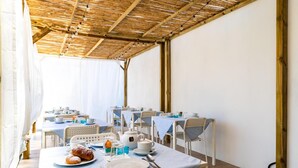 A dining area with tables set for breakfast, featuring plates, cups, and pastries. - La Smeralda - Boutique Rooms and Breakfast (Golfo Aranci)