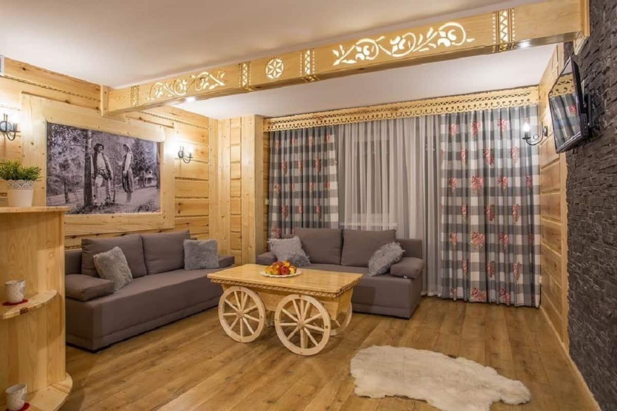 A cozy room with a wooden interior, a sofa, a small table with fruit, and a checkered curtain.