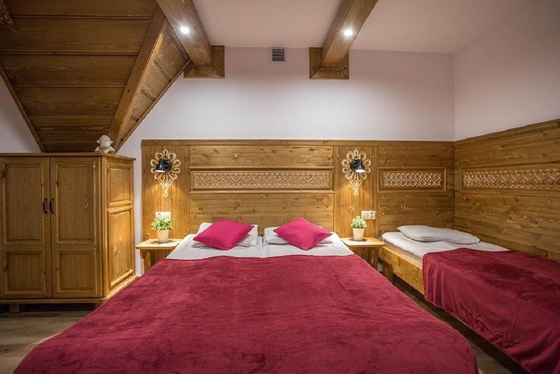 A wooden-paneled bedroom with two beds, a nightstand with lamps, and a wardrobe.