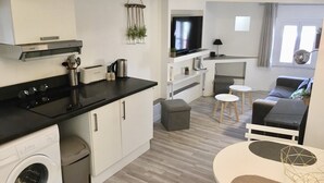 Une cuisine moderne équipée d’un four encastré, d’un lave-linge et d’un coin repas avec une table ronde et deux tabourets.