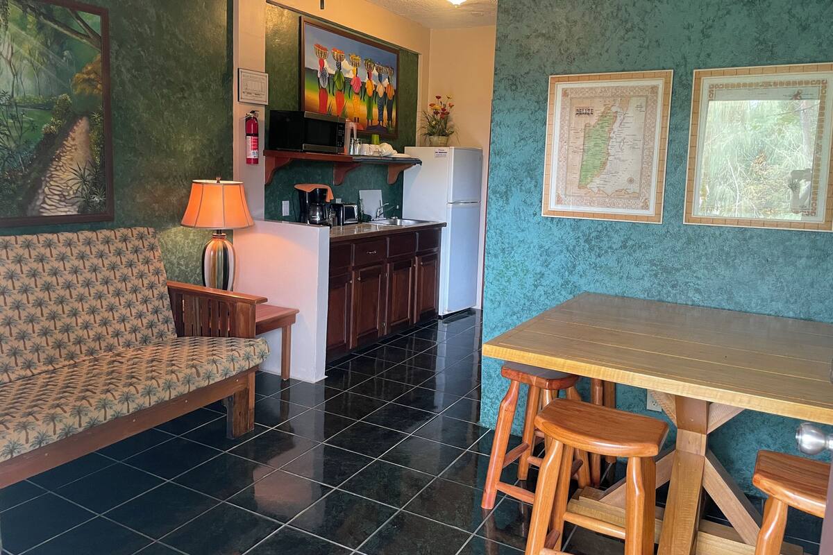 A compact kitchen with a microwave, stove, and refrigerator. There is a dining area with a table and chairs.