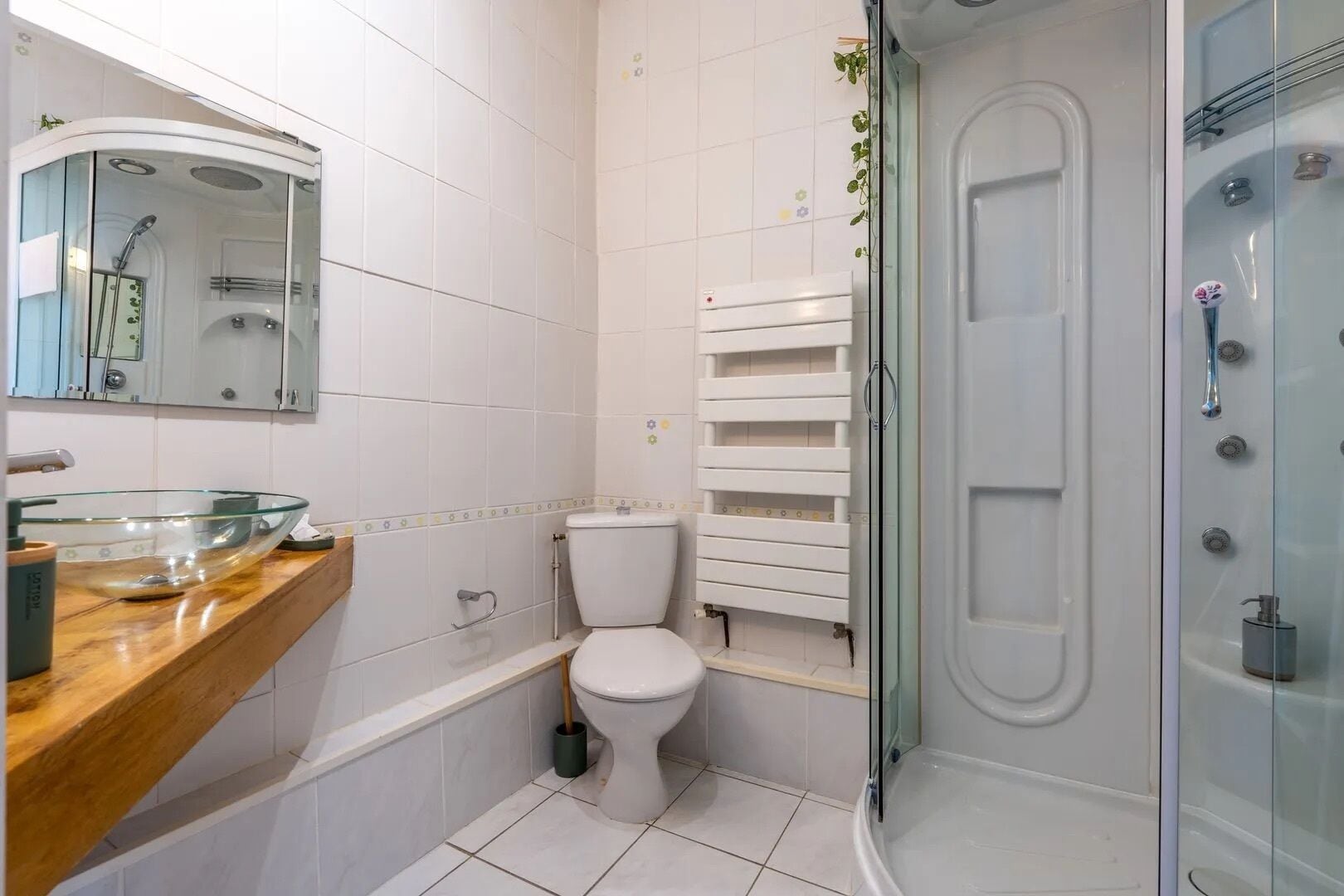 Un baño moderno con ducha envuelta en vidrio, inodoro blanco y tocador de madera con lavabo de cristal.