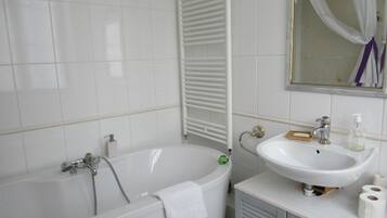 Un baño con bañera, lavabo y espejo.