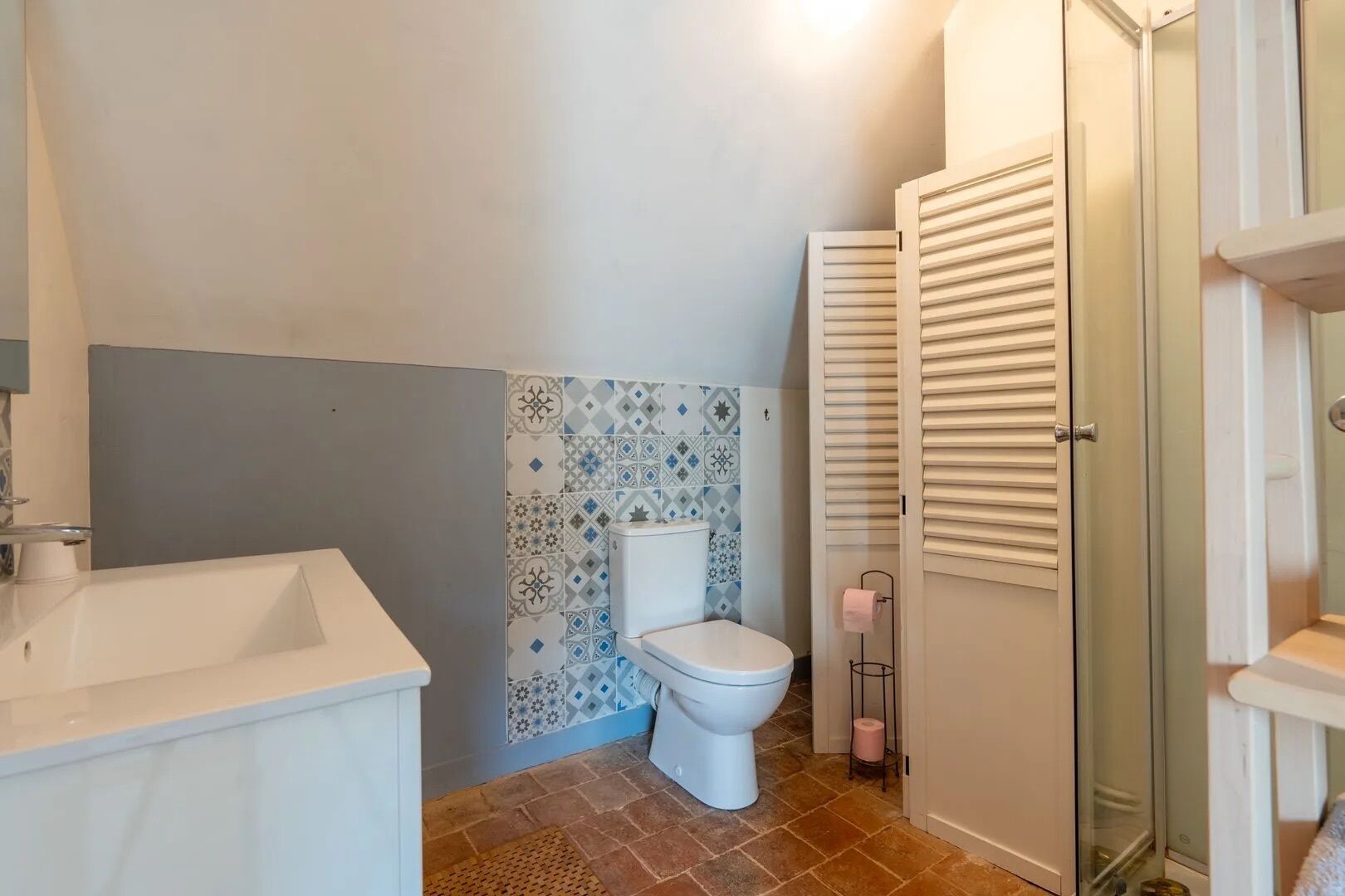 Ein Badezimmer mit weißem Waschbecken, WC und Duschbereich.