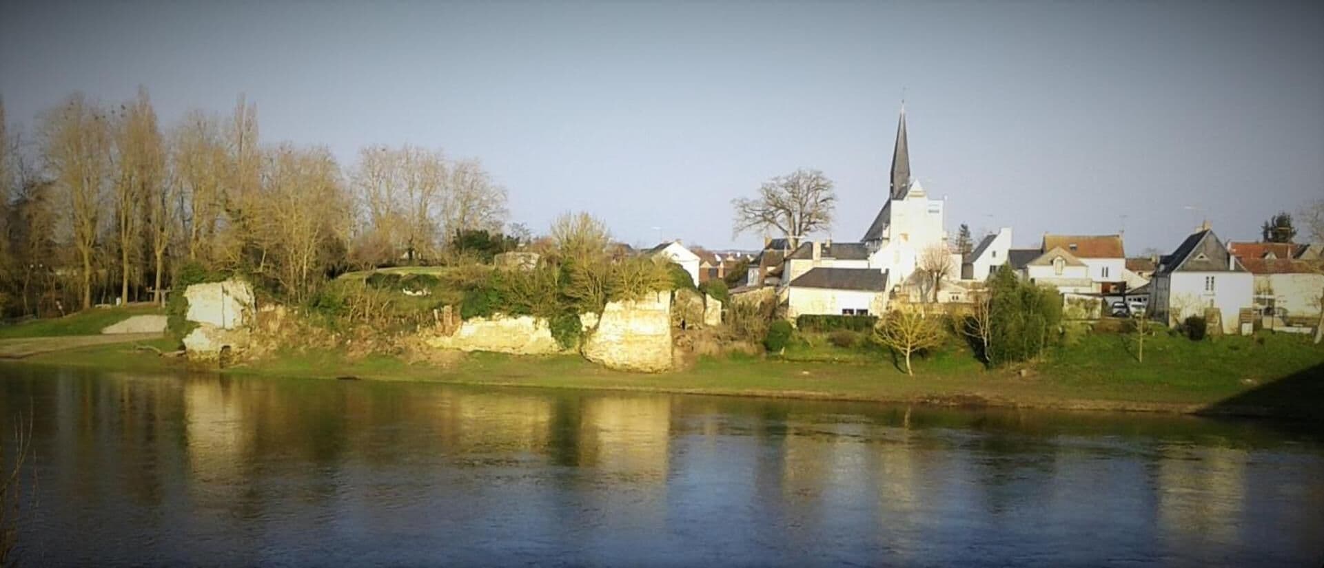 A riverside town with a prominent church, stone walls, and residential buildings.