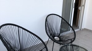 A balcony with three black wire-framed chairs and a small glass table. - KalliGeoM (Hersonissos)
