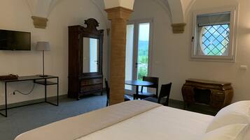 Un dormitorio con cama, escritorio, silla, cómoda, espejo y ventana con vistas.