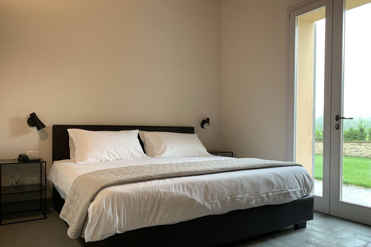 A bedroom with a large bed, two bedside tables, and a door leading to a balcony.