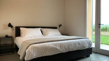 Quarto com uma cama grande, duas mesas de cabeceira e uma porta que dá para uma varanda.