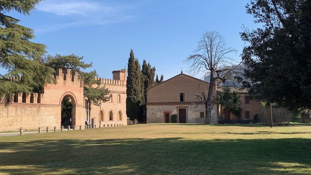 A historic building with a large arched entrance, a courtyard, and a smaller building with a tiled roof. - Palazzo Dè Rossi Hotel (Sasso Marconi)