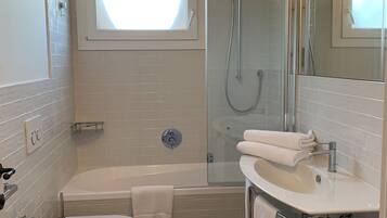 Une salle de bain moderne équipée d’une baignoire, de toilettes, d’un bidet et d’un grand miroir.