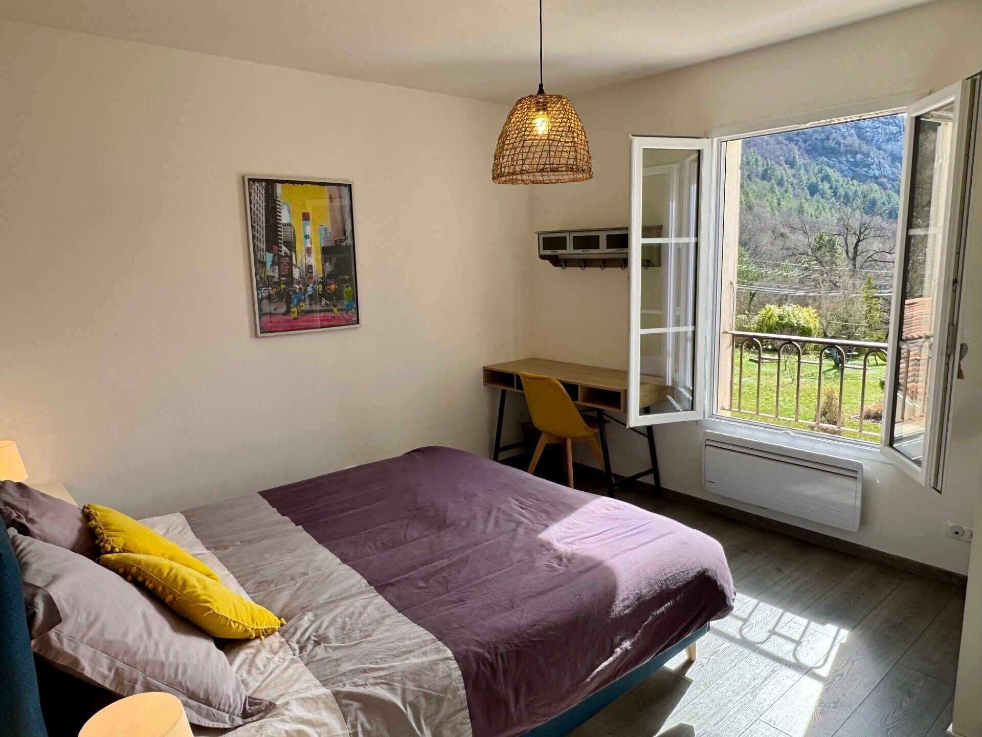 Une chambre à coucher avec un lit, un bureau et une fenêtre donnant sur un jardin.