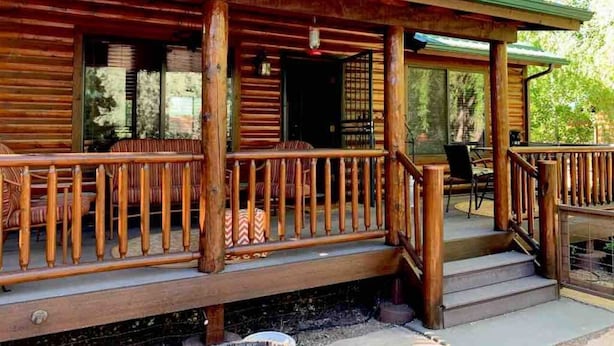 Een houten hut met een veranda, een deur en een raam.
