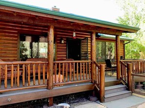 A wooden cabin with a porch, a door, and a window. - Bear Pond Cabin (Overgaard)
