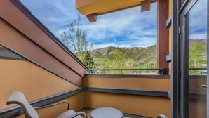 A balcony with a view of mountains, a small round table, and two chairs.