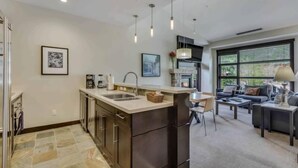 A modern kitchen with a central island, built-in appliances, and pendant lighting.