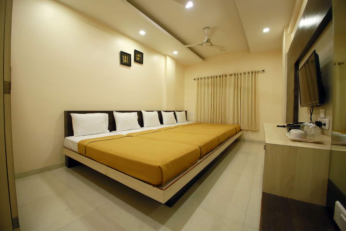 A hotel room with a large bed, a desk with a flat-screen TV, and a ceiling fan.