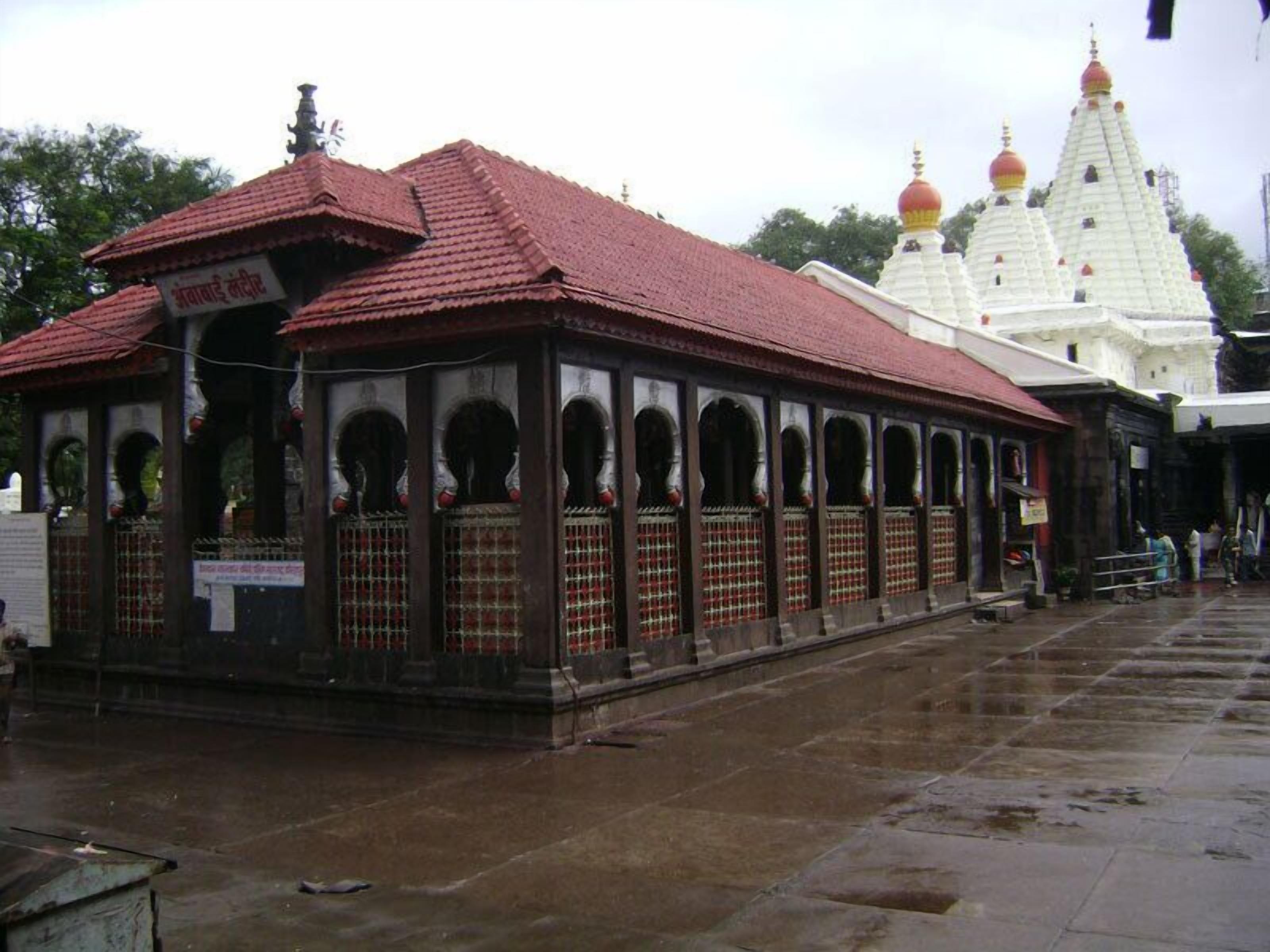 A traditional building with a tiled roof and arched windows, adjacent to a white structure with domes.