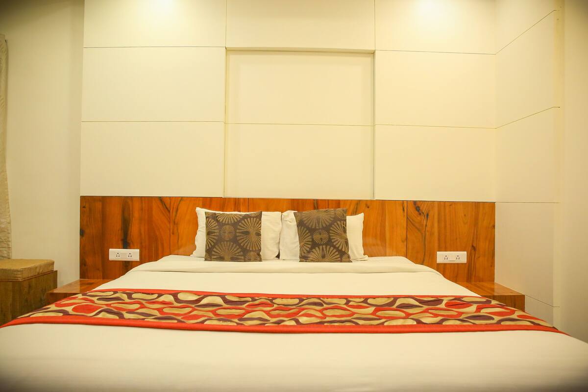 A neatly made bed with a patterned throw, a wooden headboard, and a bedside table with a lamp.