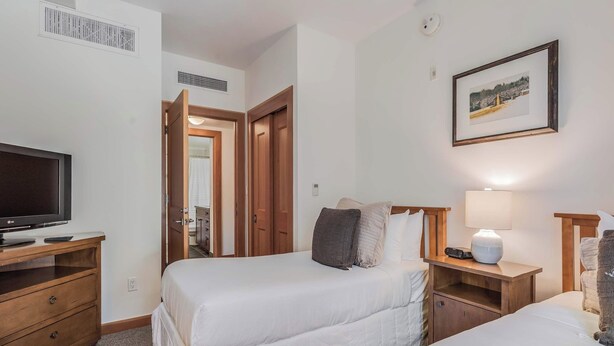 Una camera d'albergo con due letti, una televisione, un comodino con una lampada e un quadro appeso al muro.