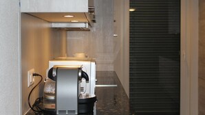 A coffee machine in a modern kitchen with a countertop and a sliding door in the background. - Euro Apartment (Interlaken)
