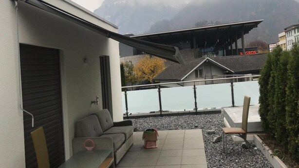 A modern building with a balcony overlooking a body of water and mountains. - Euro Apartment (Interlaken)