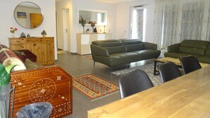 A living room with a sofa, a dining table, and a cabinet. - Euro Apartment (Interlaken)