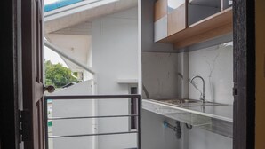 A compact kitchen with a single sink, a small countertop, and a visible water pipe. - The residence (Koh Samui)