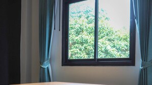 A wooden table with two matching chairs in a room with a large window and curtains. - The residence (Koh Samui)