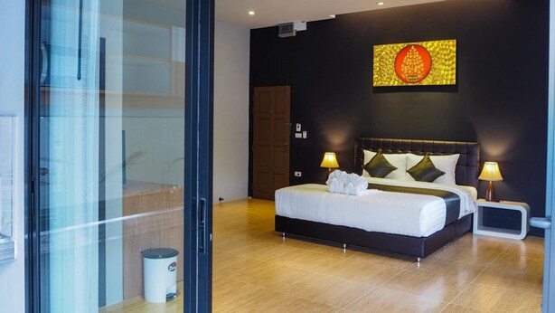 A modern hotel room with a large bed, two bedside lamps, a wall-mounted artwork, and a wooden floor. - The residence (Koh Samui)