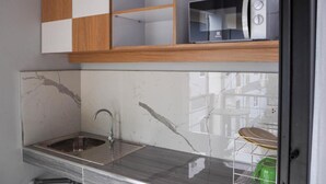 A modern kitchen with a marble countertop, a stainless steel sink, and a microwave on a wooden shelf. - The residence (Koh Samui)