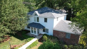 A two-story house with a front porch, a separate garage, and a well-maintained lawn.