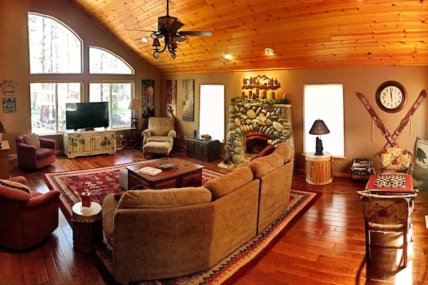Large living room with vaulted ceiling open to dining room and kitchen