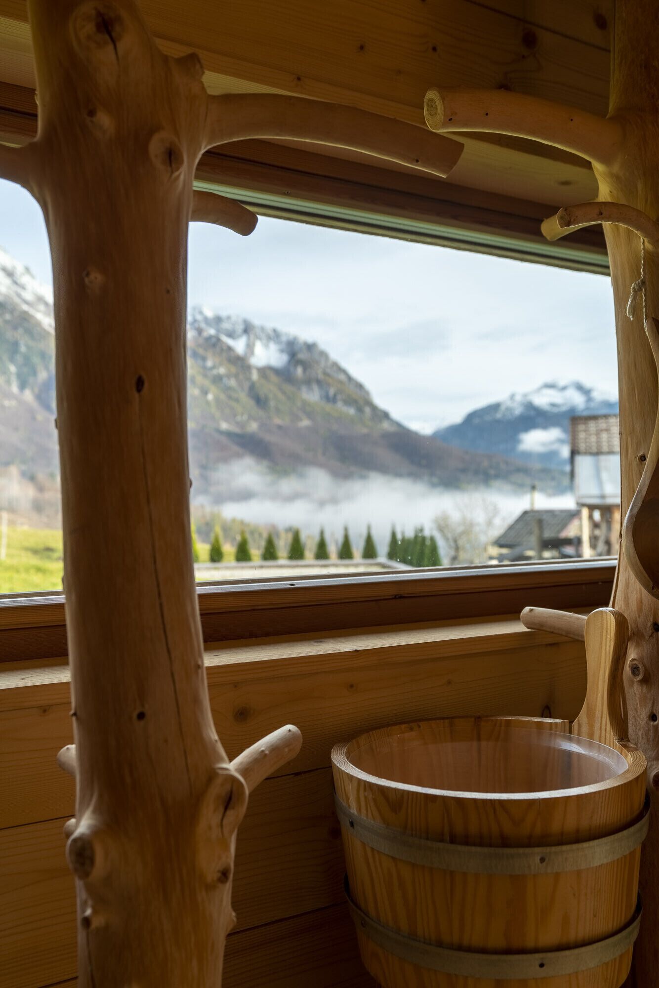 L’intérieur d’un chalet en bois rustique, doté d’une grande fenêtre offrant une vue sur les montagnes et un lac.