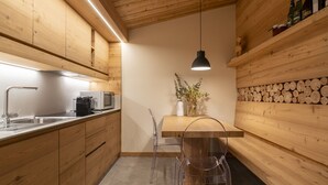 Una cocina moderna con armarios de madera, un lavamanos de acero inoxidable, un microondas y una mesa de comedor con sillas.