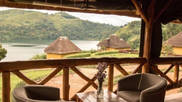 A rustic wooden structure with a thatched roof overlooking a lake and hills. - Ntoroko Game Lodge (Ntoroko)