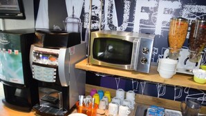 A coffee station with a coffee machine, a microwave, and various coffee cups and containers. - Hotel Design Booking (Villeneuve-le-Roi)