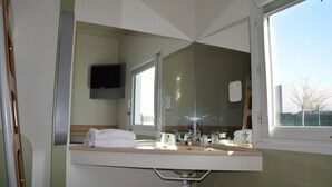 A hotel bathroom with a large mirror, a sink, a toilet, and a window. - Hotel Design Booking (Villeneuve-le-Roi)