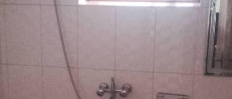 A bathroom with a shower, a window, and a sink.