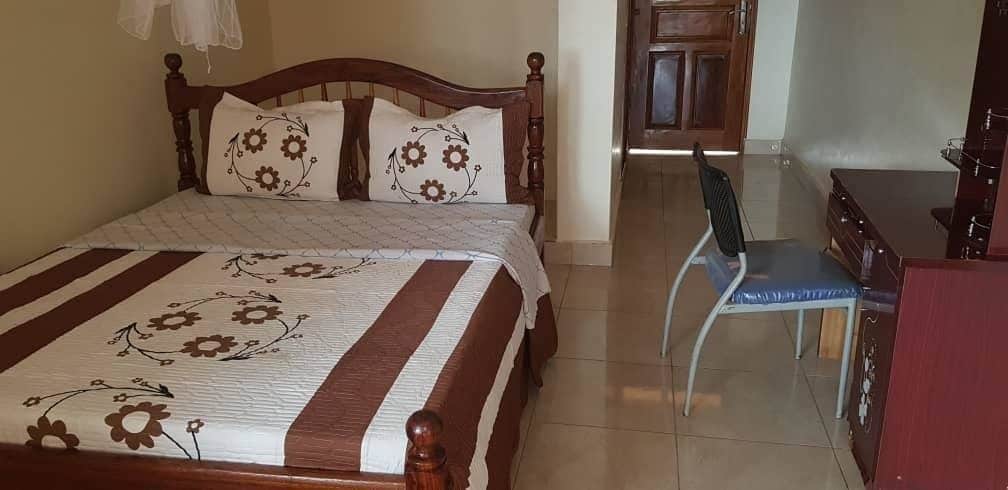 A bedroom with a bed, a chair, a desk, and a wardrobe.