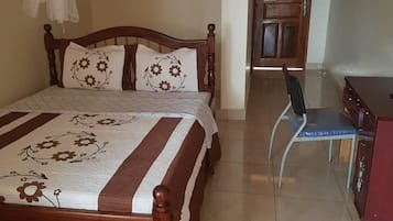 A bedroom with a bed, a chair, a desk, and a wardrobe.