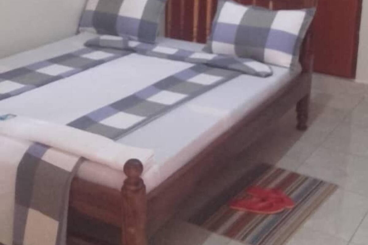 Un dormitorio con una cama de madera, un armario rojo y una mosquitera blanca.