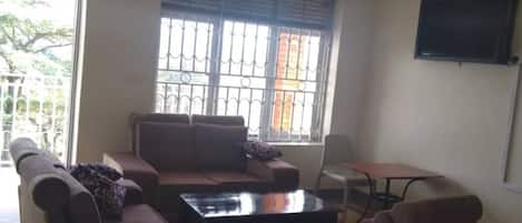 Uma sala de estar com um sofá, uma mesa de centro e uma televisão na parede.
