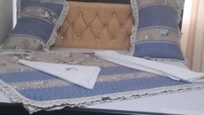 Un lit doté d’une tête de lit capitonnée, d’une couvre-lit à motifs et de deux oreillers.