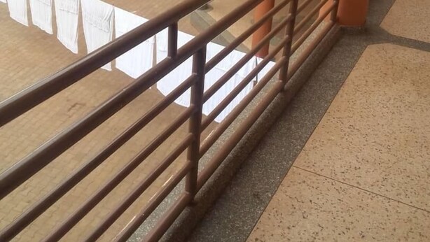 Un immeuble à plusieurs étages doté de balcons, de garde-corps et d’une antenne parabolique.