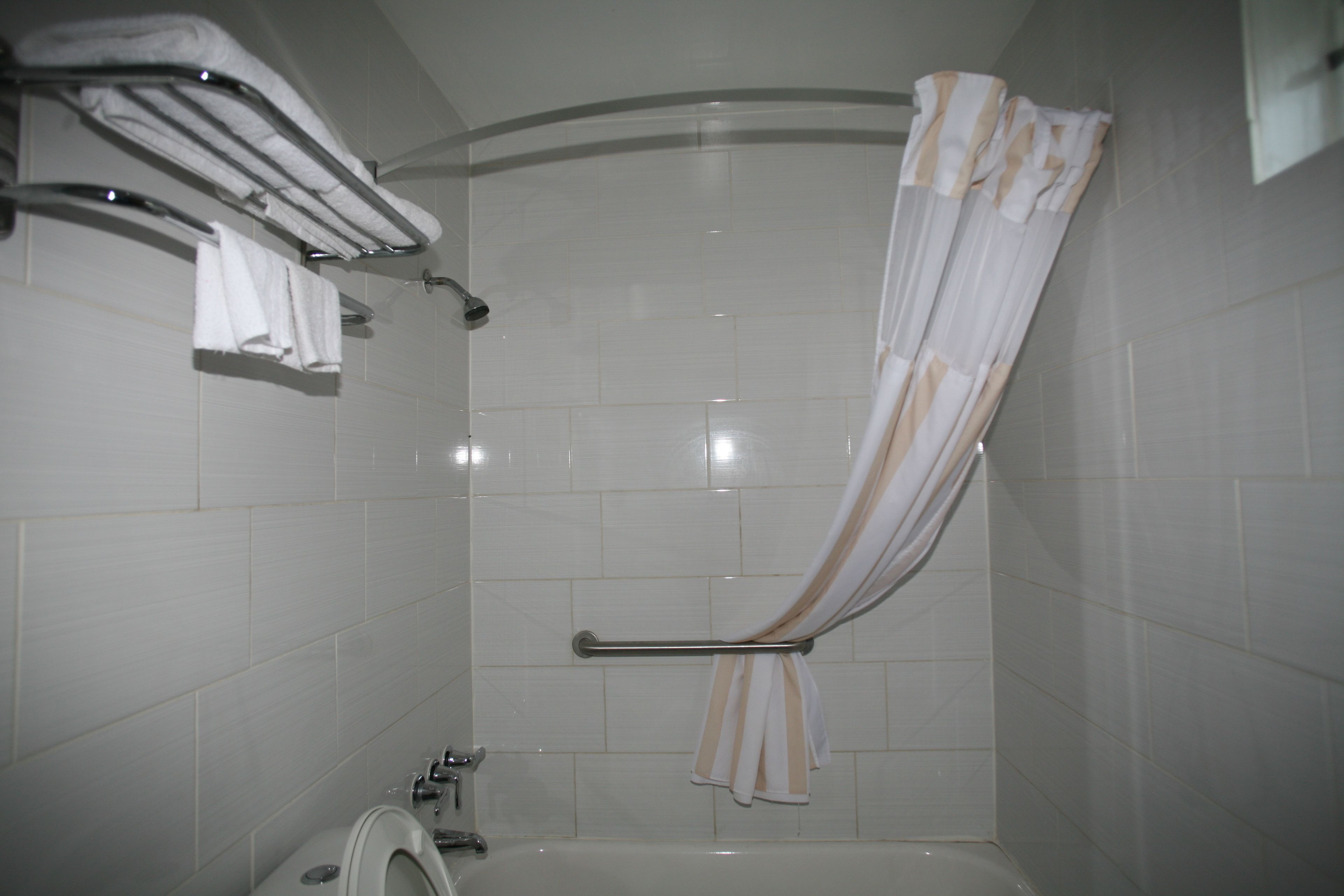 A bathroom with a shower, a toilet, and a towel rack with towels.
