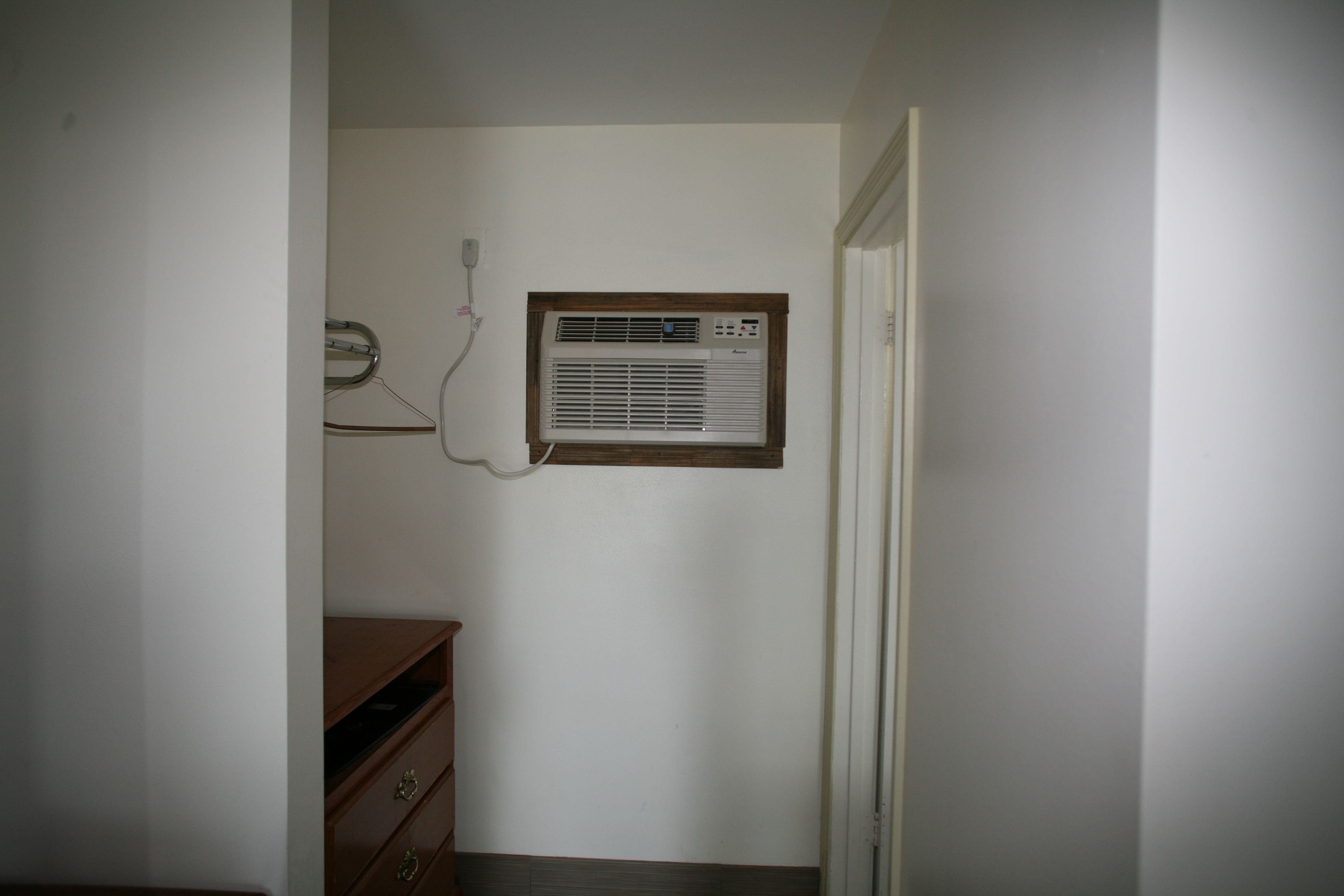 Una habitación con aire acondicionado de pared, un aparador de madera y una puerta.