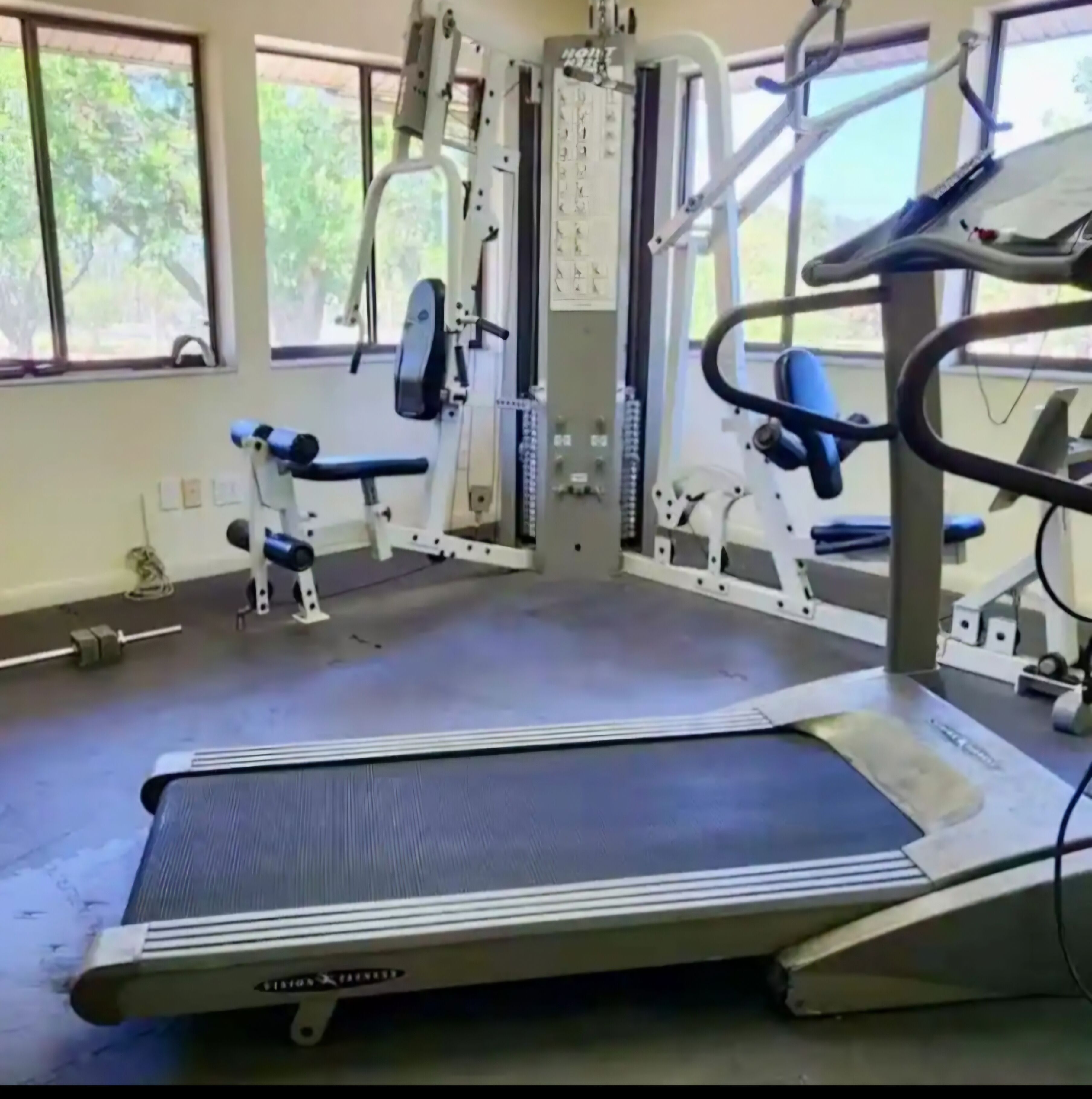 A gym with a treadmill, weight machines, and a bench.