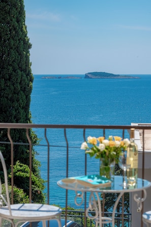 A balcony with a view of the sea, a table with a vase of flowers, and a chair. - Guest House Medine (Zupa dubrovacka)